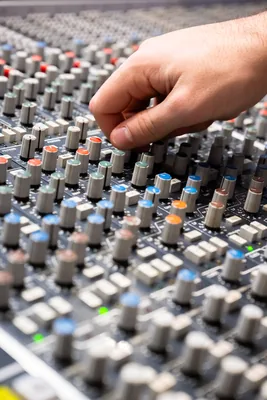 Main d'ingénieur du son ajustant les potentiomètres d'une console de mixage