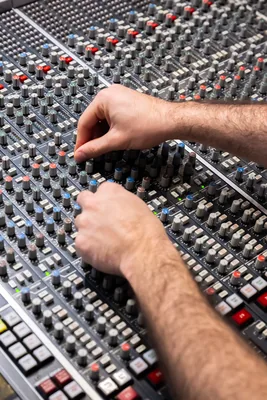 Deux mains réglant l'égalisation sur une console de mixage analogique