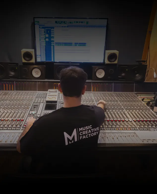 Étudiant de dos mixant sur une grande console analogique en studio