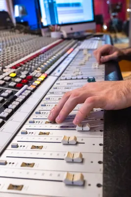 Main d'ingénieur du son réglant les faders d'une console de mixage en studio